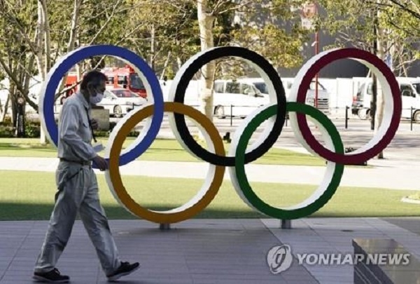 마스크를 착용한 한 남성이 2020 도쿄올림픽 오륜 조형물 앞을 지나가고 있다. 사진=연합뉴스