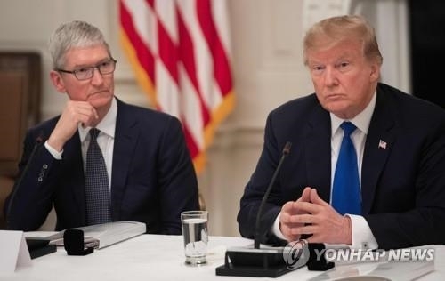 팀 쿡 애플 CEO와 나란히 앉은 트럼프 대통령. 미중 무역전쟁속에서 트럼프 대통령은 애플 편에 섰고, 애플은 리쇼어링을 통해 미국내 일자리를 늘리는데 협조했다. 사진=AFP/연합뉴스