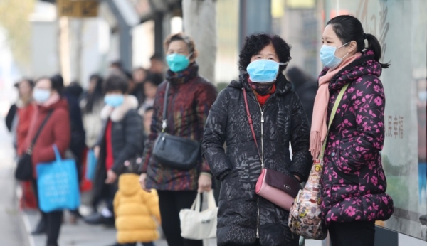 중국 후베이성 우한의 주민들이 마스크를 쓴 채 신종 코로나바이러스에 의한 폐렴 발병의 근원지로 지목돼 폐쇄된 화난 해산물 도매시장 인근 버스 정류소에서 버스를 기다리고 있다. 사진=EPA/연합뉴스