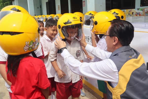 안전모 전달식에 참여한 조정래 KB손해보험 인니법인장이 Sinar Cahaya Kasih 학교 학생들에게 안전모를 씌워주고 있다. 사진 제공=KB손보